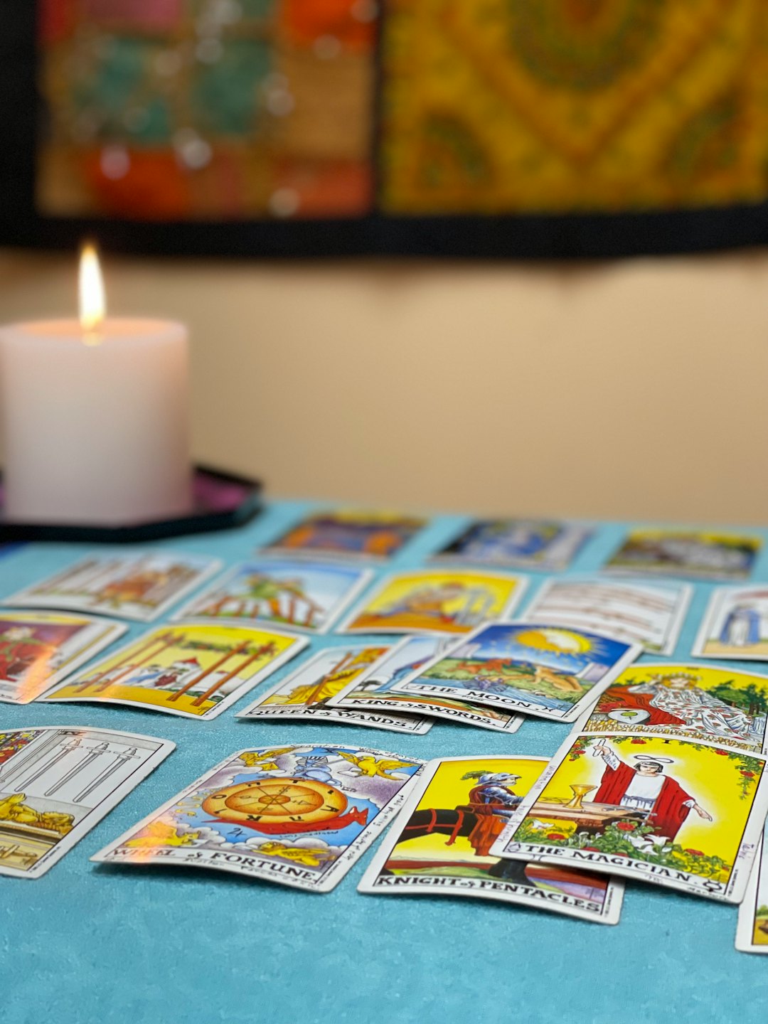 Tarot cards spread out on a blue tablecloth with a candle.